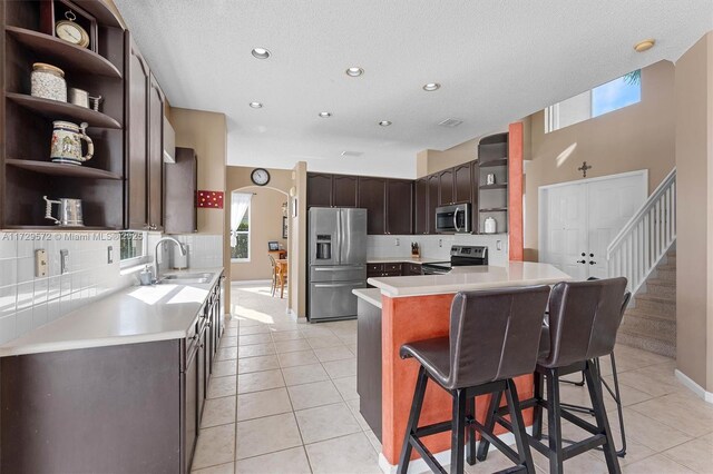 kitchen featuring a breakfast bar area, sink, stainless steel appliances, and light tile patterned flooring