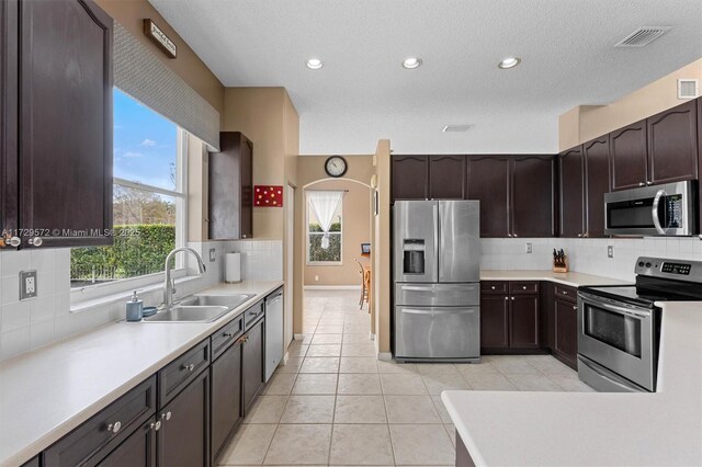 kitchen featuring light tile patterned floors, stainless steel appliances, plenty of natural light, tasteful backsplash, and sink