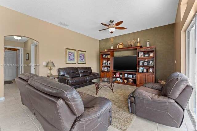 living room featuring a textured ceiling, ceiling fan, and light tile patterned floors