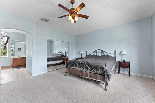 carpeted bedroom featuring a textured ceiling, ceiling fan, connected bathroom, and sink