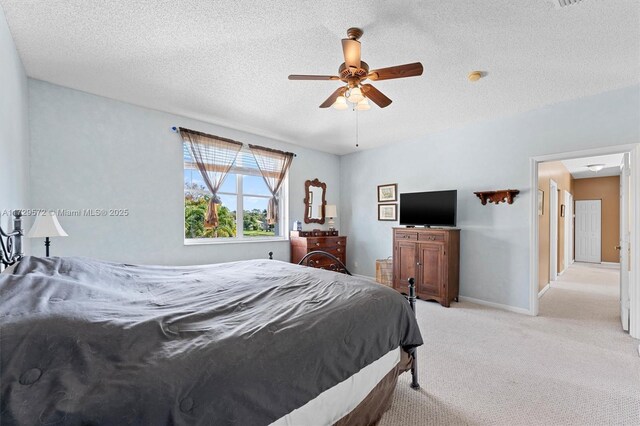 carpeted bedroom featuring ceiling fan and a textured ceiling