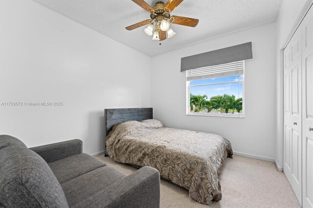 carpeted bedroom with ceiling fan, a textured ceiling, and a closet