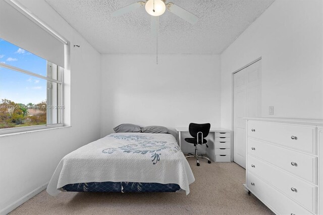 bedroom featuring ceiling fan, light colored carpet, and a textured ceiling