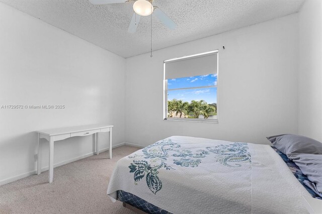 bedroom featuring ceiling fan, light colored carpet, and a textured ceiling