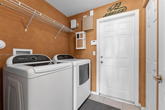 washroom with a textured ceiling, tile patterned floors, and independent washer and dryer