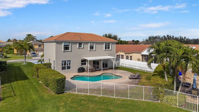 rear view of property with a patio area, a fenced in pool, and a lawn