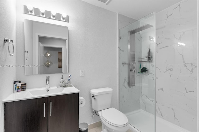 bathroom featuring toilet, vanity, and a tile shower