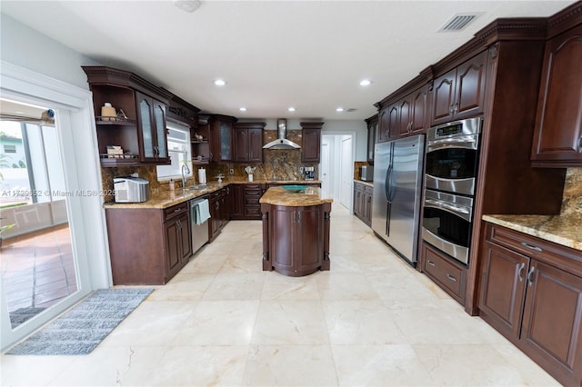 kitchen featuring dark brown cabinetry, sink, a kitchen island, and wall chimney range hood