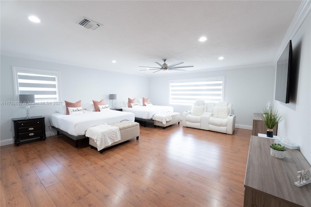 bedroom with multiple windows, ornamental molding, ceiling fan, and light hardwood / wood-style flooring