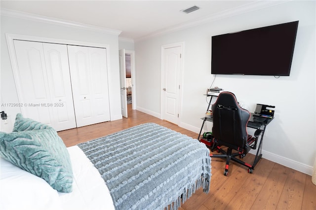 bedroom featuring hardwood / wood-style flooring, crown molding, and a closet