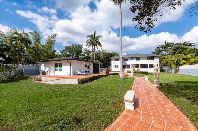 rear view of house featuring a lawn and a patio