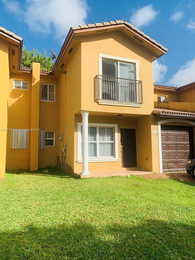 rear view of house with a balcony, a yard, and a garage