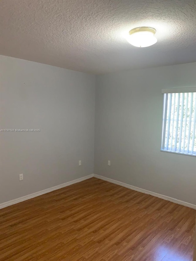 empty room featuring a textured ceiling and hardwood / wood-style floors