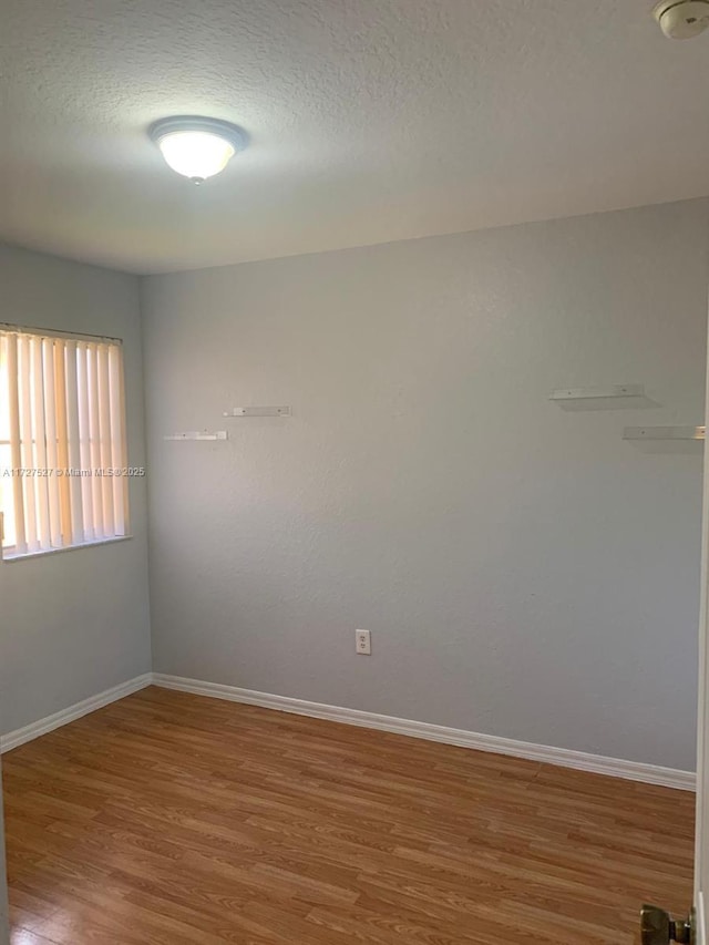 unfurnished room with a textured ceiling and wood-type flooring