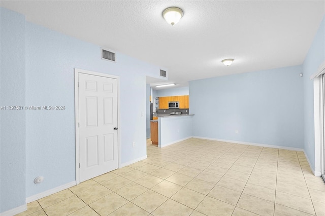 tiled empty room featuring a textured ceiling