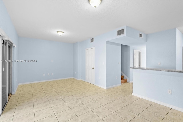 spare room with a textured ceiling and light tile patterned flooring