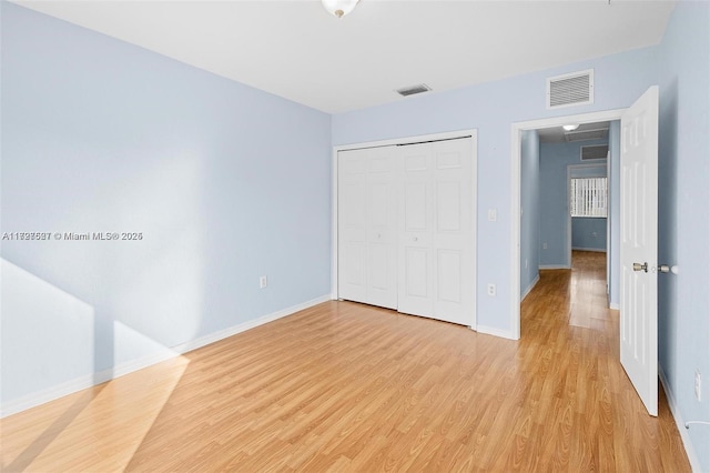 unfurnished bedroom with light wood-type flooring and a closet