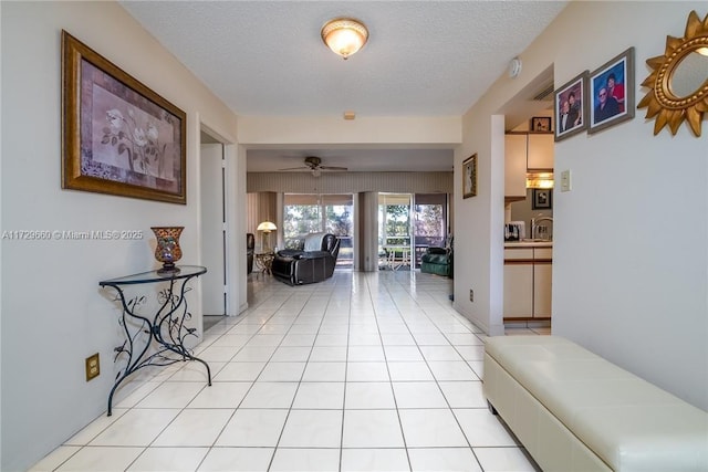 corridor featuring light tile patterned flooring, sink, and a textured ceiling