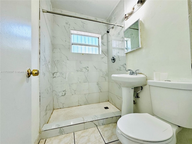 bathroom with toilet, a tile shower, and tile patterned floors