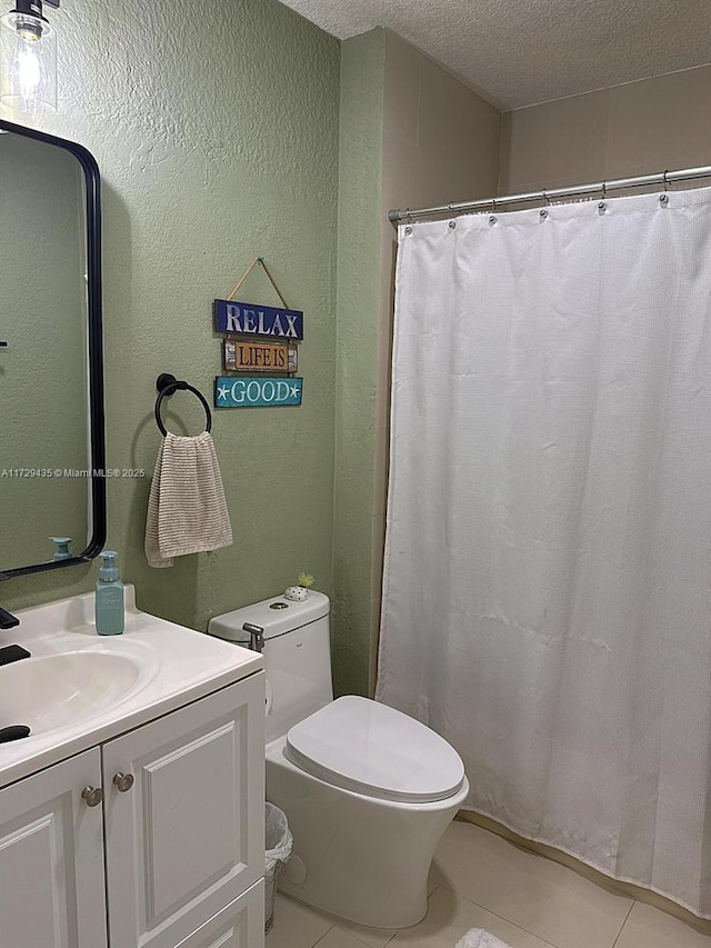 bathroom featuring tile patterned flooring, vanity, a textured ceiling, and toilet