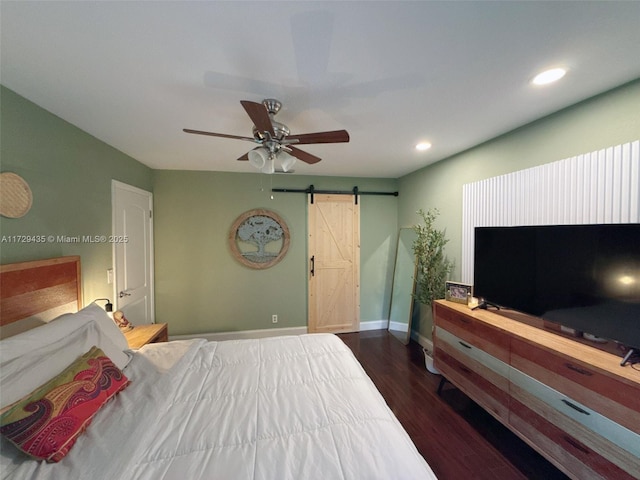 bedroom with dark wood-type flooring, a barn door, and ceiling fan