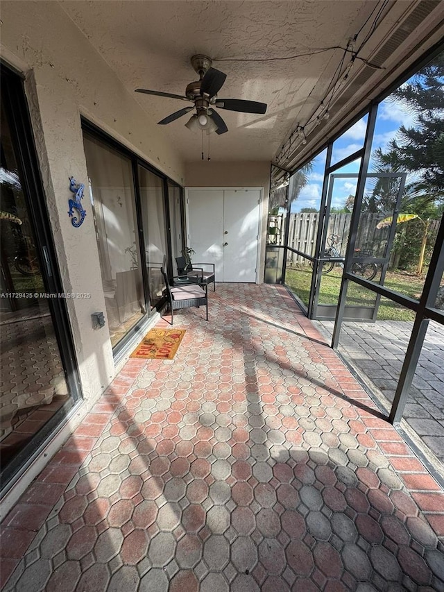 unfurnished sunroom with ceiling fan