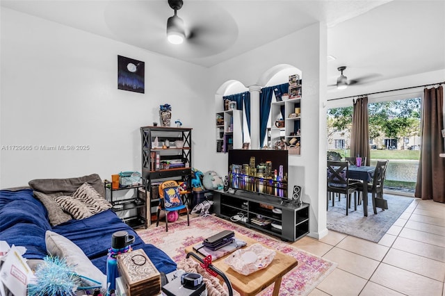 living room featuring ceiling fan, light tile patterned floors, and decorative columns