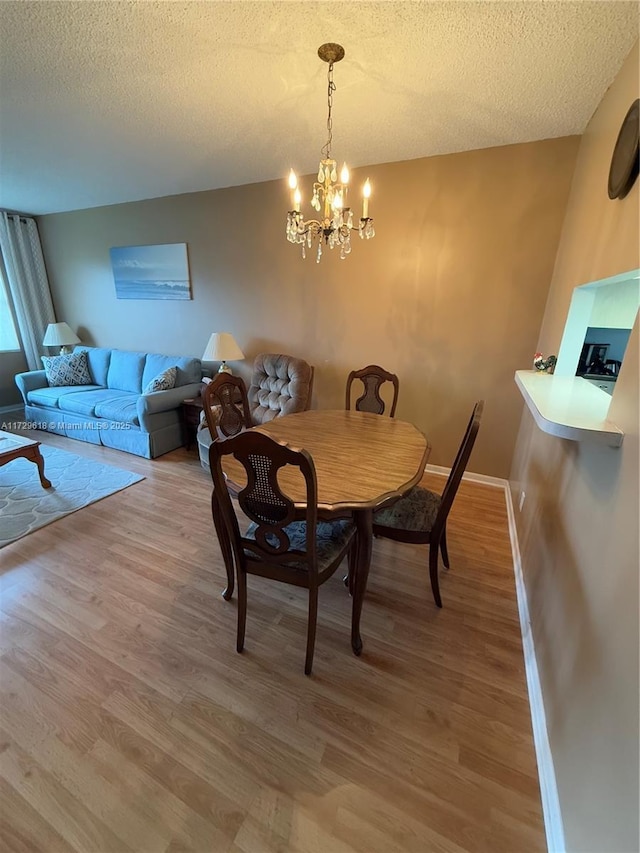 dining room featuring hardwood / wood-style floors, a textured ceiling, and a notable chandelier