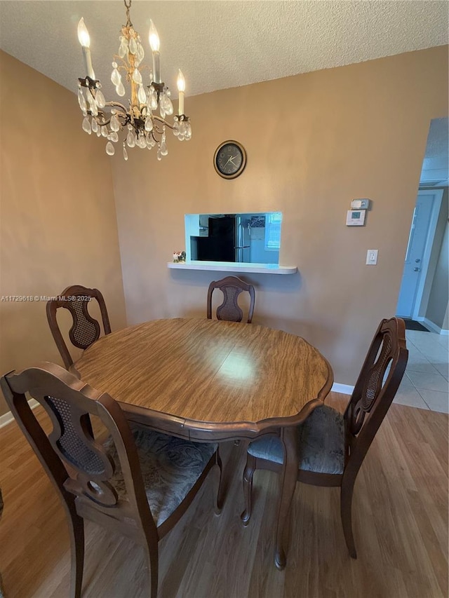 tiled dining room featuring a notable chandelier and a textured ceiling