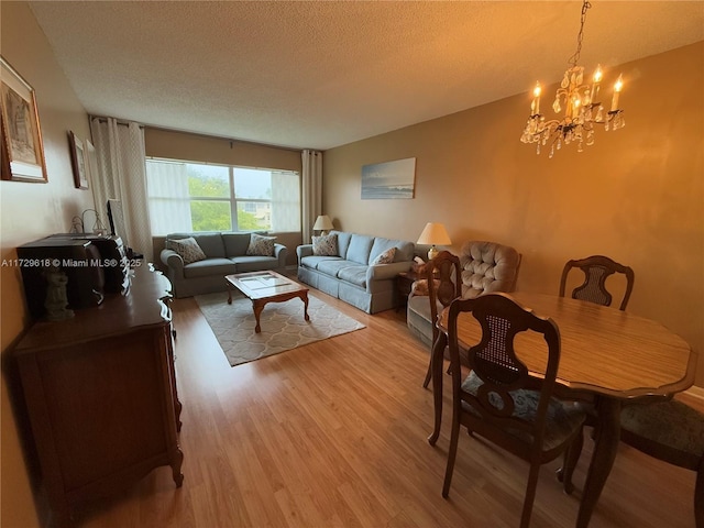 living room featuring a textured ceiling, a chandelier, and light hardwood / wood-style floors