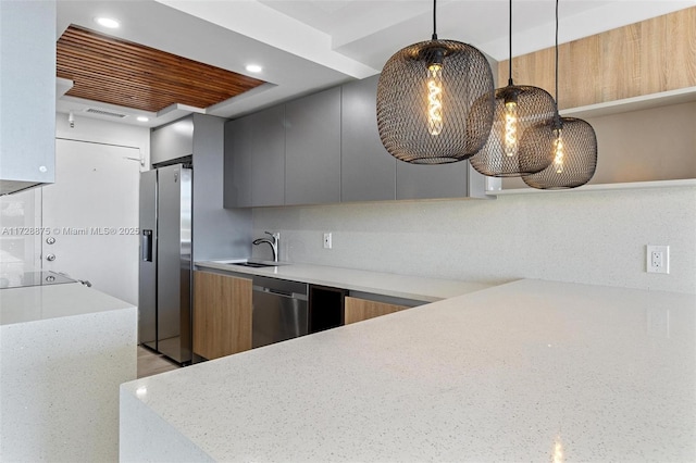 kitchen featuring appliances with stainless steel finishes, decorative backsplash, hanging light fixtures, light stone countertops, and sink