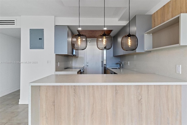 kitchen with hanging light fixtures, decorative backsplash, kitchen peninsula, and electric panel