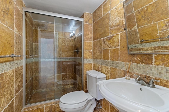 bathroom with toilet, backsplash, sink, and a shower with shower door