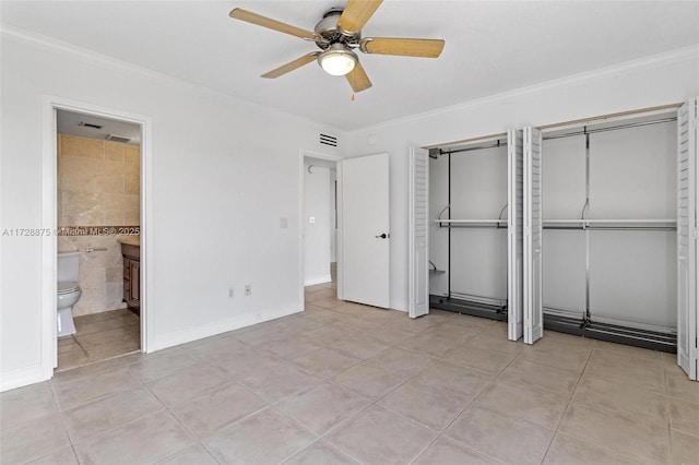 unfurnished bedroom featuring a closet, light tile patterned flooring, ceiling fan, ensuite bathroom, and crown molding