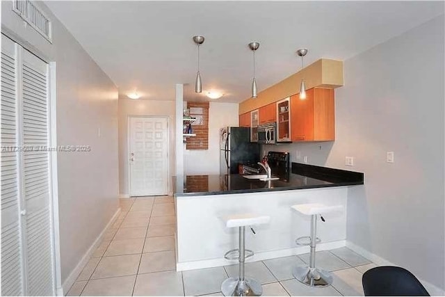 kitchen with hanging light fixtures, kitchen peninsula, a breakfast bar area, and stainless steel appliances