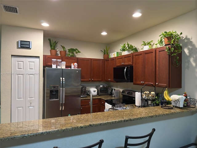 kitchen with light stone counters, stainless steel appliances, and kitchen peninsula