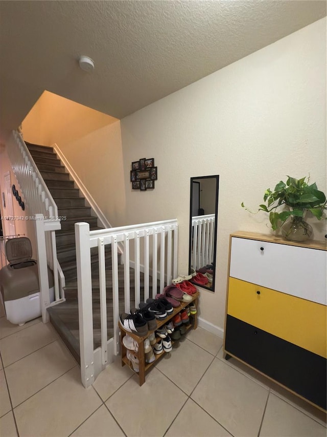 stairway featuring a textured ceiling and tile patterned floors