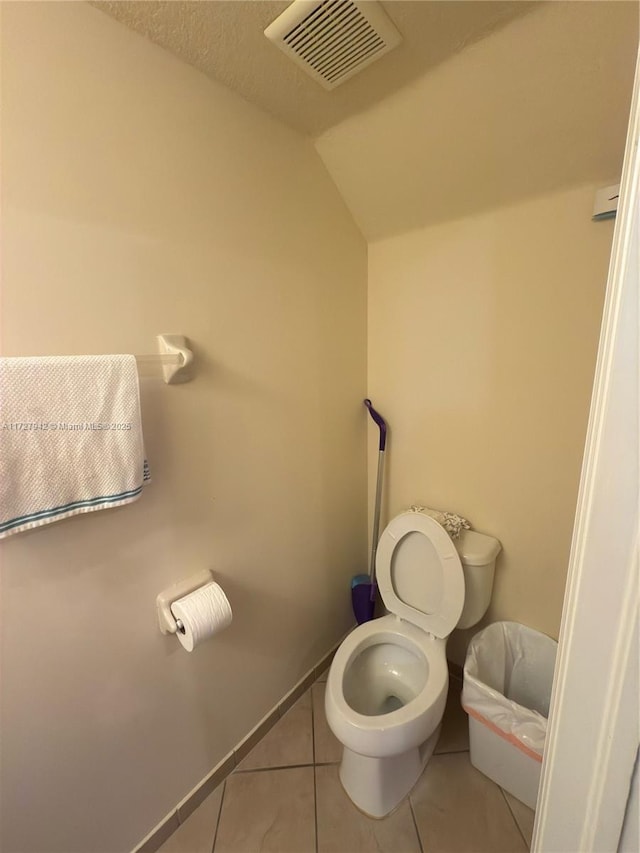 bathroom with toilet, tile patterned floors, a textured ceiling, and lofted ceiling