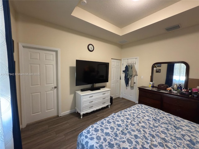 bedroom with a raised ceiling and dark hardwood / wood-style flooring