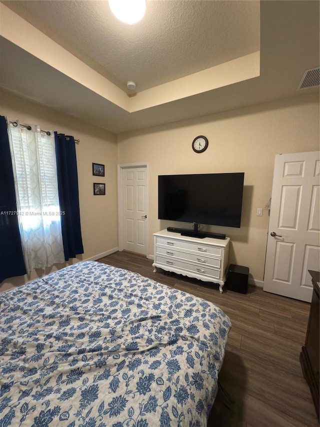 bedroom featuring dark wood-type flooring and a raised ceiling