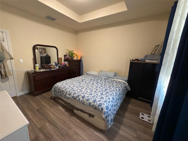 bedroom featuring a raised ceiling and dark hardwood / wood-style flooring