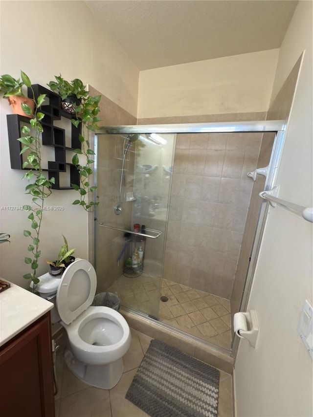 bathroom featuring toilet, tile patterned flooring, a shower with door, and vanity