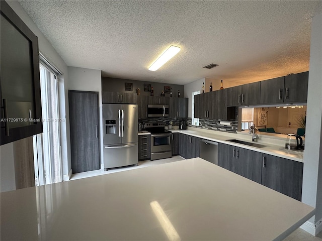 kitchen featuring decorative backsplash, sink, a textured ceiling, and appliances with stainless steel finishes