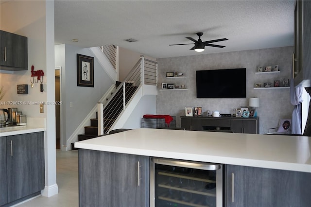 bar featuring ceiling fan, a textured ceiling, beverage cooler, and dark brown cabinets