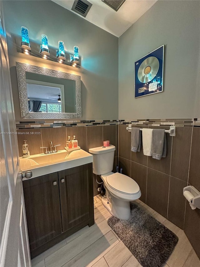 bathroom with tile patterned floors, toilet, vanity, and tile walls