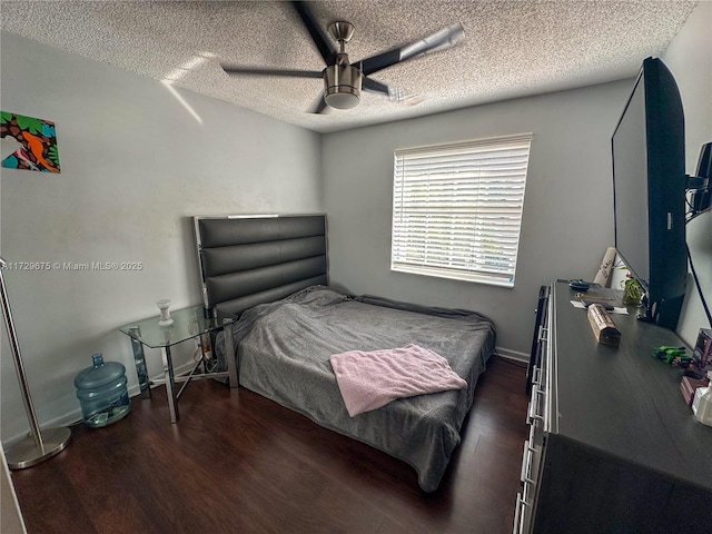 bedroom with ceiling fan, dark wood-type flooring, and a textured ceiling