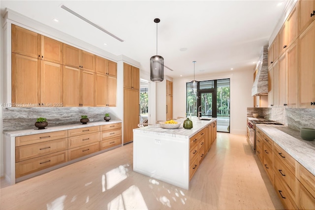 kitchen featuring a center island with sink, stainless steel range, hanging light fixtures, custom range hood, and sink