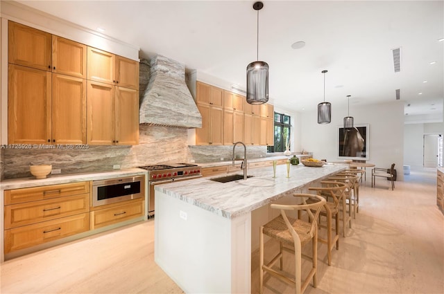 kitchen with pendant lighting, double oven range, sink, a kitchen island with sink, and custom range hood