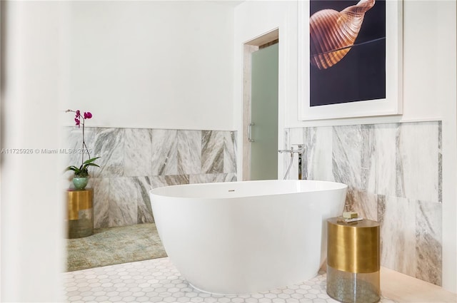 bathroom featuring tile patterned flooring, tile walls, and a tub to relax in