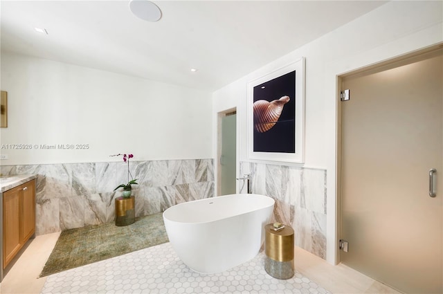 bathroom with a washtub, tile walls, tile patterned floors, and vanity